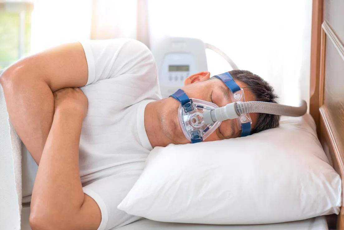 Homme dormant dans son lit et portant un masque CPAP, thérapie de l'apnée du sommeil.